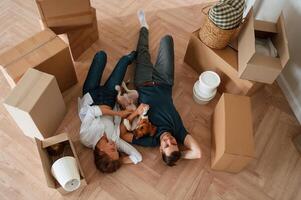 On, the floor, lying down, top view. Young couple with dog are moving to new home photo