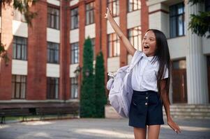 Hello gesture by the hand. School girl in uniform is outdoors near the building photo