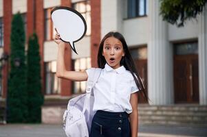 Sticker ,with, ,thoughts, copy ,space for text. School girl in uniform is outdoors near the building photo