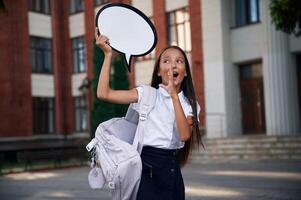 Sticker with thoughts, copy ,space for text.. School girl in uniform is outdoors near the building photo