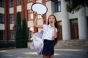 Sticker with thoughts, copy space, for, text. School girl in uniform is outdoors near the building photo