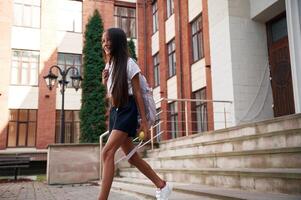Going out from the building.,. School girl in uniform is outdoors photo
