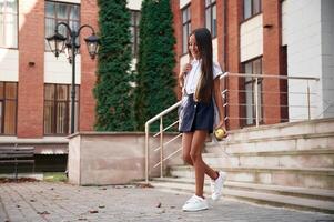 Going ,out from, the building. School girl in uniform is outdoors photo