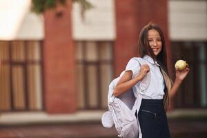 Outdoors, near the building. School girl in uniform photo