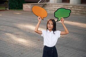 The choice. Holding banners with no text, copy space. School girl in uniform is outdoors near the building photo