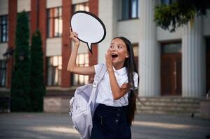 Sticker ,with thoughts, copy space for text. School girl in uniform is outdoors near the building photo