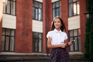 Orange colored building. ,School girl in uniform is outdoors photo