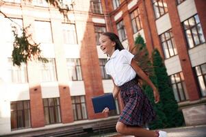Going, out ,from ,the building. School girl in uniform is outdoors photo