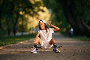 Chilling, sitting and relaxing. Happy little girl with skateboard outdoors photo