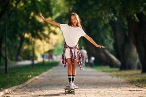 Controlling ,the balance.. Happy little girl with skateboard outdoors photo