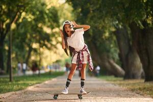 On the road in park., Happy little girl with skateboard outdoors photo