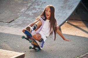 On the ramp. Happy, little, girl with skateboard outdoors photo