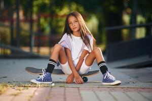 Conception ,of ,extreme sports. Happy little girl with skateboard outdoors photo