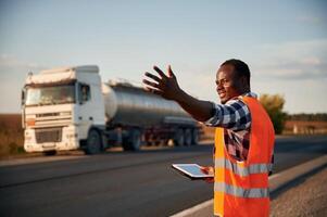 Showing ,the way.. Black man is standing on the road with truck on it photo