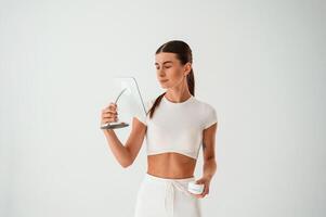 Young woman is standing with cream for the face. In the studio photo