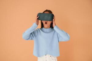 Trying VR glasses. Cute ,young girl is in the studio against background photo