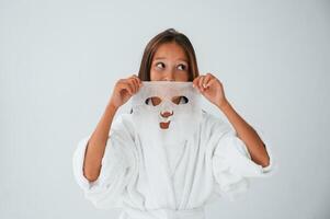 Wearing off ,mask for the face. Conception of beauty and self care. Young girl is in the studio photo