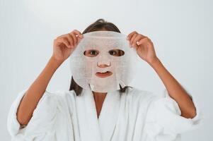 Wearing off mask for the ,face. Conception of beauty and self care. Young girl is in the studio photo