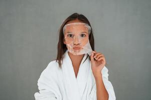 Funny, facial, expression.. Playing with mask. Conception of beauty. Young girl is in the studio photo