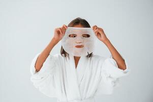 Playing and holding ,mask for the face. Conception of beauty and self care. Young girl is in the studio photo