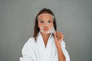 Cleaning mask, is on the face. Conception of beauty and self care. Young girl is in the studio photo