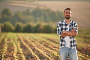 With arms crossed. Man is on the agricultural field, conception of work and harvest photo