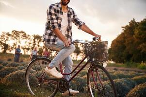 Handsome man in casual clothes is with bicycle on the agricultural field near greenhouse photo