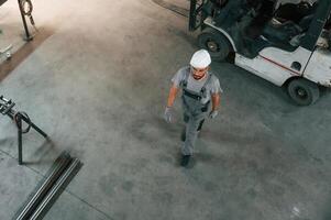 Near, the, forklift, top view. Young factory worker in grey uniform photo