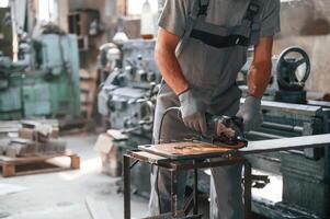 Polishing the surface with angle grinder. Close up view of man that is working at the factory photo