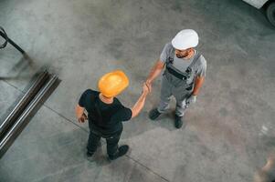 Top view ,of two ,factory workers that are standing and making handshake, business deal photo
