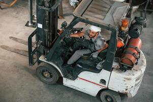 View, from the top, in the forklift. Young factory worker in grey uniform photo