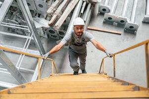 Climbing up, on ,the ladder. Young factory worker in grey uniform photo
