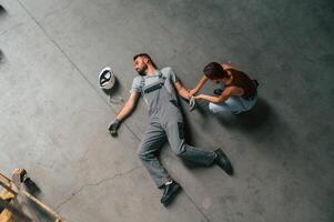 Woman hands checking pulse... Accident, male factory worker fell, without consciousness, lying down on the floor photo