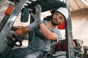 Hand ,gestures. In the forklift. Young factory worker in grey uniform photo