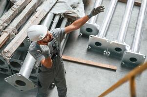 Top view. Making gesture, by ,hands. Young factory worker in grey uniform photo
