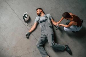 Woman hands checking pulse.. Accident, male factory worker fell, without consciousness, lying down on the floor photo