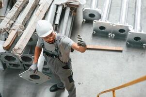 Making ,gesture, by hands. Young factory worker in grey uniform photo