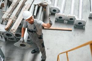 Making ,,gesture by hands. Young factory worker in grey uniform photo