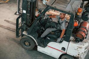 View ,from the top, in the forklift. Young factory worker in grey uniform photo