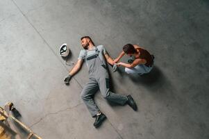 Woman ,hands, checking pulse.. Accident, male factory worker fell, without consciousness, lying down on the floor photo