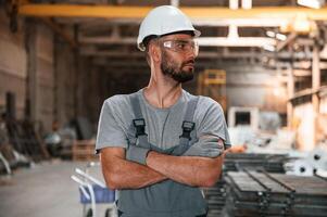Standing with arms crossed.. Young factory worker in grey uniform photo