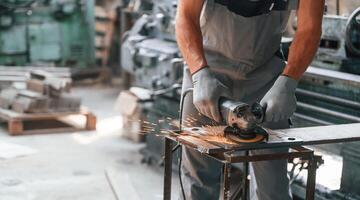 Polishing ,the surface with angle grinder. Close up view of man that is working at the factory photo