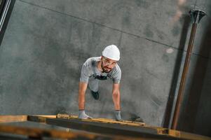 Going up on the ladder, top ,view. Young factory worker in grey uniform photo