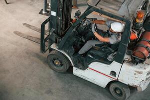 View, from, the top, in the forklift. Young factory worker in grey uniform photo