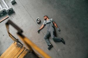 Accident, male, factory, worker fell, without consciousness, lying down on the floor photo