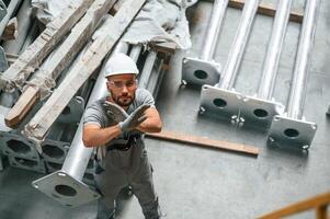 Top,, view. Making gesture by hands. Young factory worker in grey uniform photo