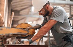 Sitting and working. Young,, man at the factory in grey uniform photo
