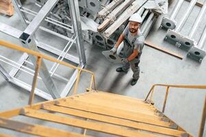 Climbing, up on the ladder. Young factory worker in grey uniform photo