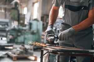 Polishing the surface with, angle grinder. Close up view of man that is working at the factory photo