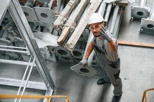 Making gesture by hands... Young factory worker in grey uniform photo